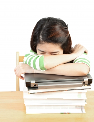 Student sleeping on stack of books